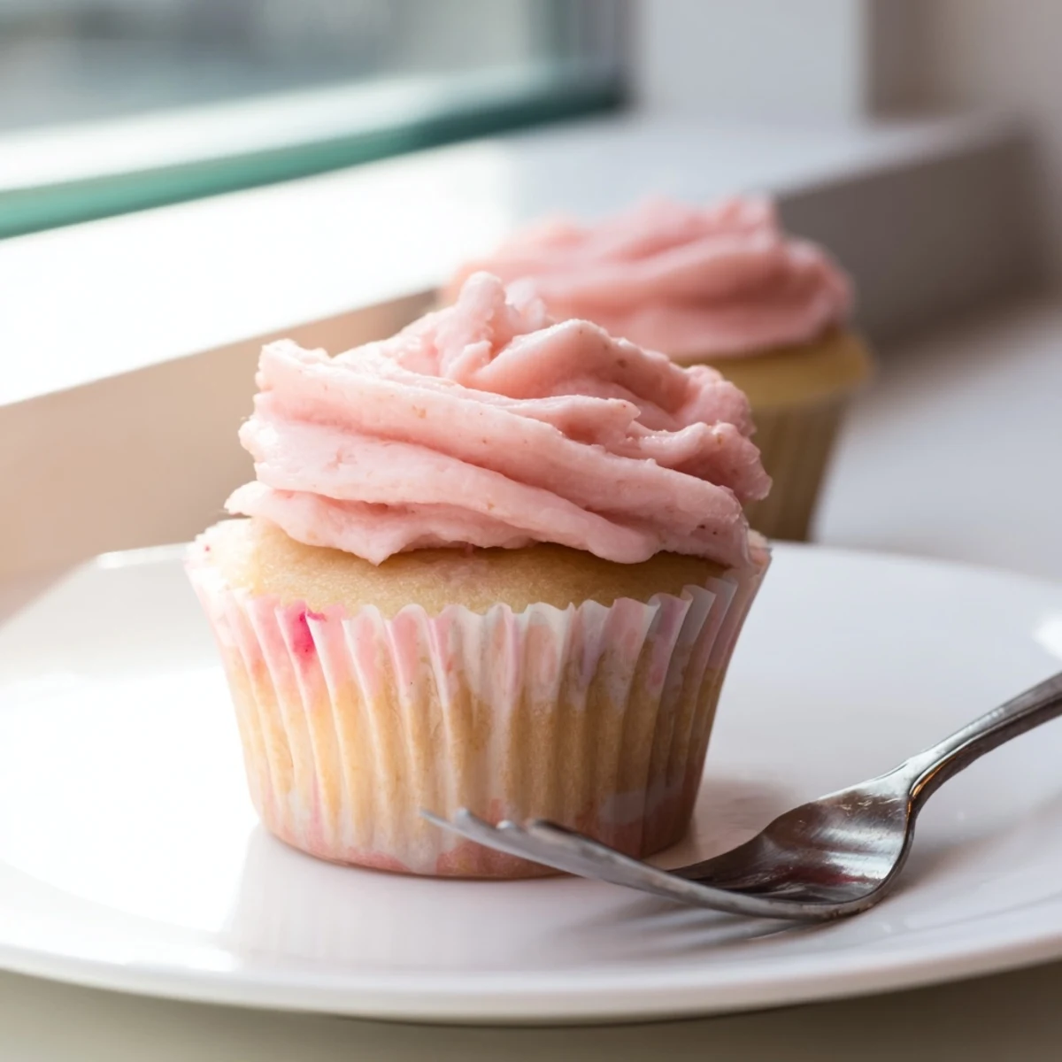 Golden lemon cupcakes with fluffy pink strawberry buttercream frosting and fresh berry garnish