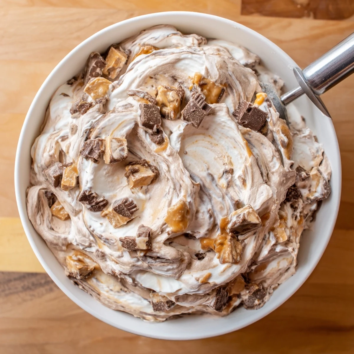 Scoop of rich Ninja Creami Phish Food ice cream topped with gooey marshmallow ribbons and chocolate fish pieces