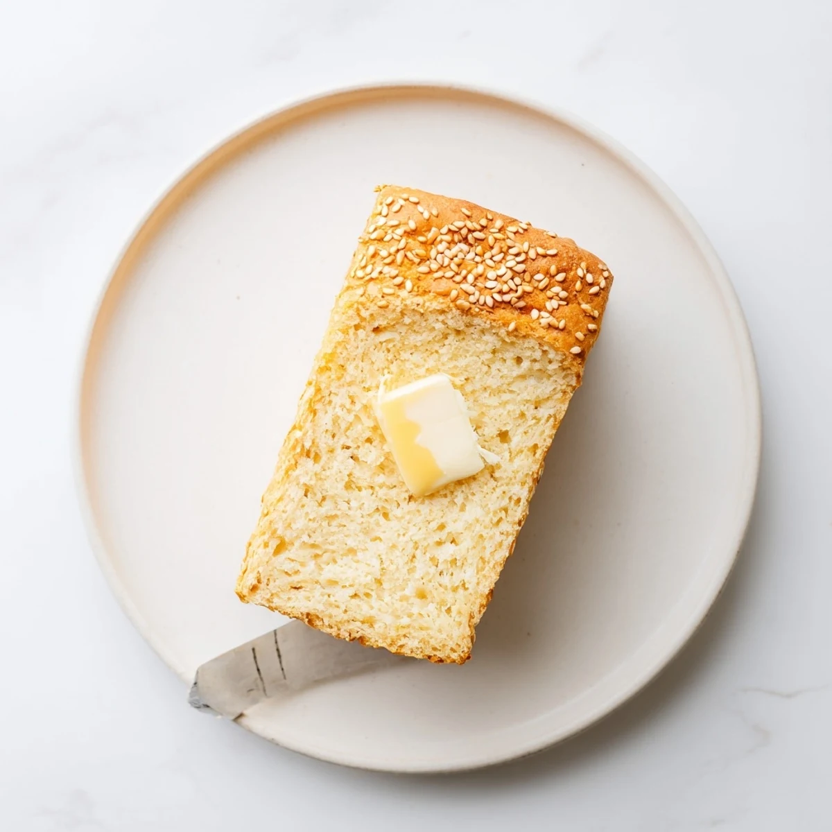 Golden zero carb yogurt bread loaf sliced on wooden board with melted butter