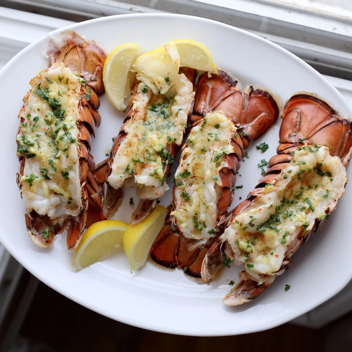 Whole roasted lobster tails swimming in buttery garlic glaze ready for elegant dinner service