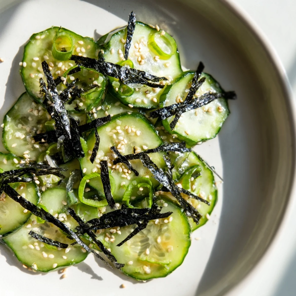 Crisp sushi cucumber salad topped with nori strips and sesame seeds in bowl