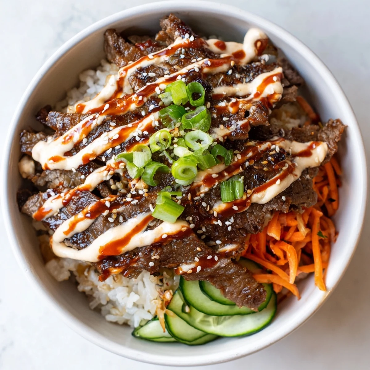 Crisp veggies and spicy cream sauce drizzled over Korean BBQ steak rice bowls
