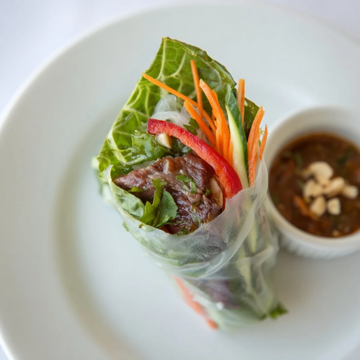 Homemade Thai Basil Beef Rolls wrapped in translucent rice paper, served with dipping sauce.