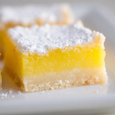 Tangy sweet lemon bars cut into squares showing bright yellow custard filling